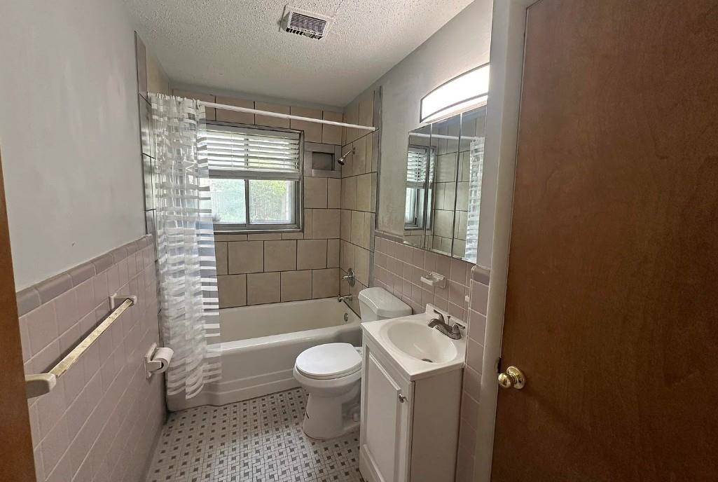 1204 Wilbec Road Memphis, TN 38117 - Photo 3 of 5 Full bath featuring tile walls, shower / bath combo with shower curtain, vanity, a textured ceiling, and a wainscoted wall