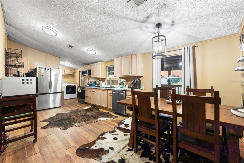 1075 Southwest Rucks Dairy Road Okeechobee, FL 34974 - Photo 43 of 65 a kitchen with stainless steel appliances kitchen island granite countertop a table chairs and a refrigerator