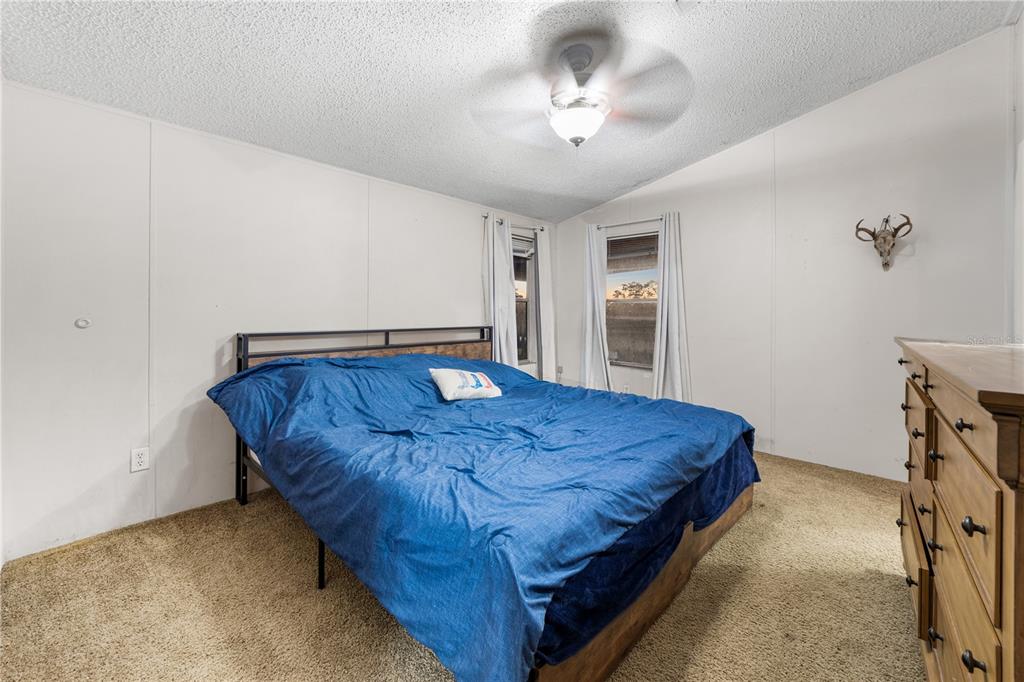 1075 Southwest Rucks Dairy Road Okeechobee, FL 34974 - Photo 63 of 65 a bed sitting in a spacious bedroom next to a window and a chandelier