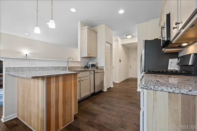 a kitchen with stainless steel appliances granite countertop white cabinets and a stove a refrigerator with wooden floor