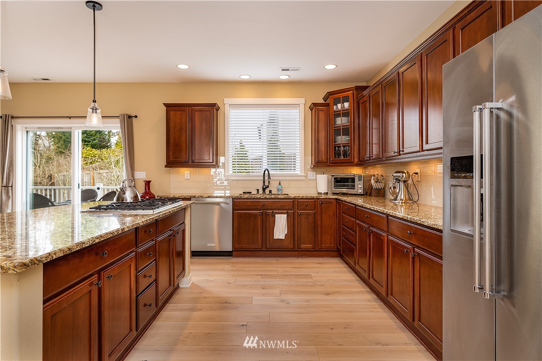 3909 219th Street Southeast Bothell, WA 98021 - Photo 3 of 34 a kitchen with stainless steel appliances granite countertop a stove a sink dishwasher a refrigerator and a oven with wooden floor