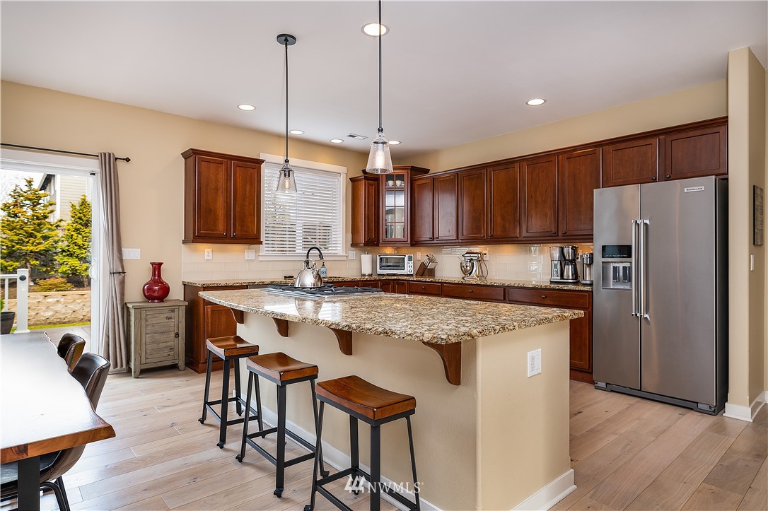 3909 219th Street Southeast Bothell, WA 98021 - Photo 4 of 34 a kitchen with stainless steel appliances granite countertop a table chairs sink refrigerator and microwave