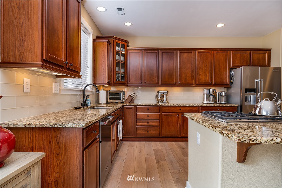 3909 219th Street Southeast Bothell, WA 98021 - Photo 5 of 34 a kitchen with granite countertop stainless steel appliances a stove sink and cabinets
