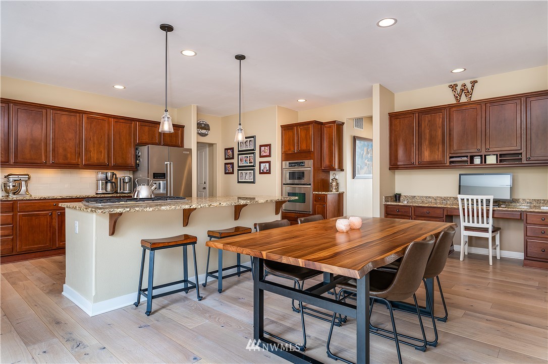 3909 219th Street Southeast Bothell, WA 98021 - Photo 7 of 34 a kitchen with stainless steel appliances granite countertop a table chairs sink refrigerator and cabinets