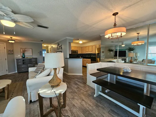 a living room with couches a dining table and kitchen view with wooden floor