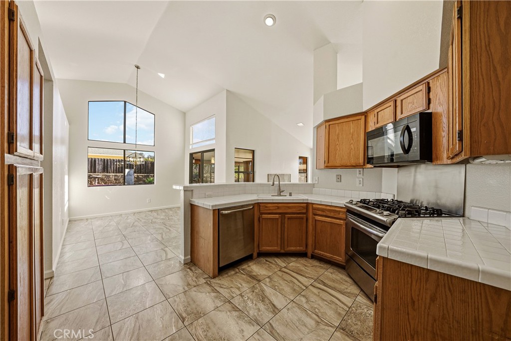 483 Violet Avenue Nipomo, CA 93444 - Photo 7 of 47 a kitchen with stainless steel appliances granite countertop a stove top oven a sink dishwasher and white cabinets with wooden floor