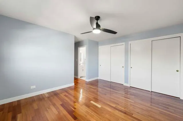 a view of an empty room with wooden floor and chandelier