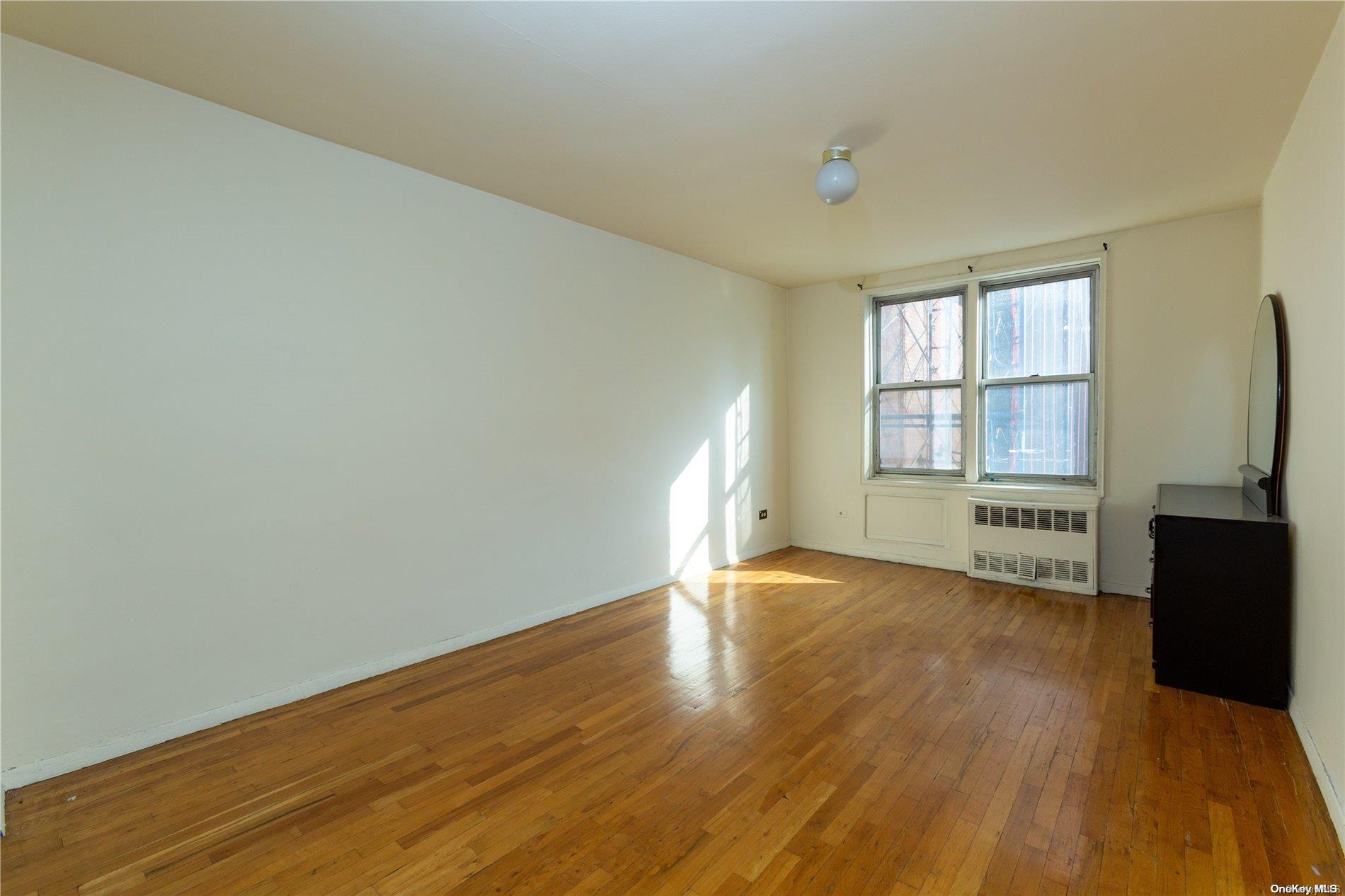 41-07 Bowne Street, Unit 3K Queens, NY 11355 - Photo 13 of 17 an empty room with wooden floor and windows