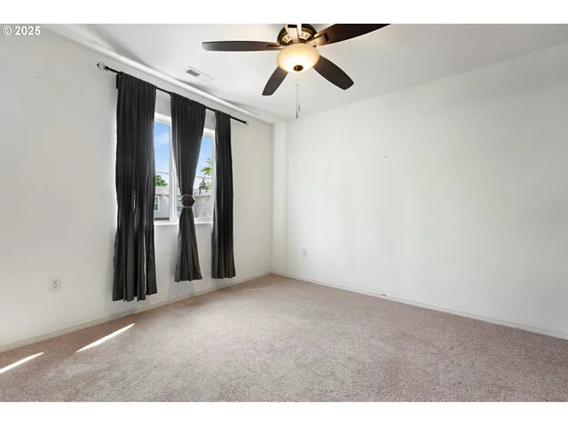 a view of an empty room with chandelier fan and a window