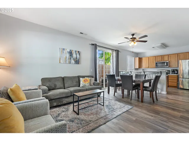 a living room with furniture and a dining table with wooden floor