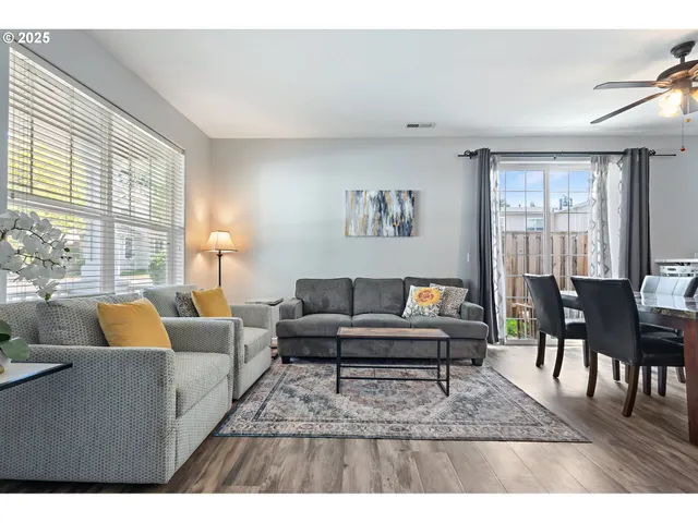 a living room with furniture a large window and a dining table