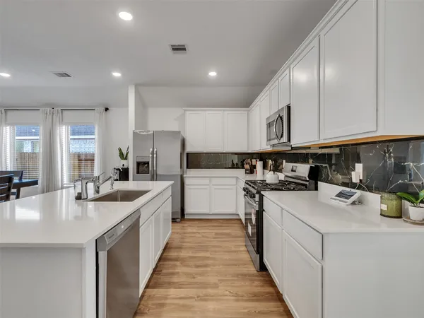 a kitchen with stainless steel appliances granite countertop a sink a stove and a refrigerator