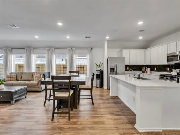 a living room with stainless steel appliances kitchen island granite countertop a dining table chairs stove a refrigerator and cabinets