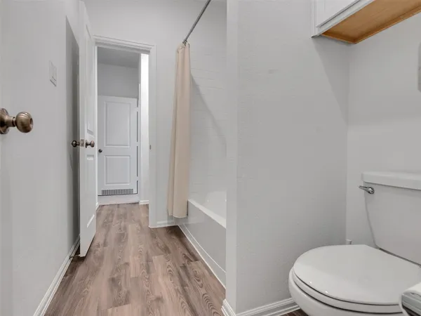 a bathroom with a toilet and a wooden floor