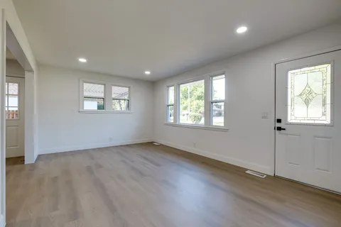 an empty room with wooden floor and windows