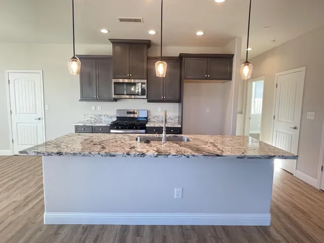a kitchen with kitchen island granite countertop wooden cabinets and a refrigerator
