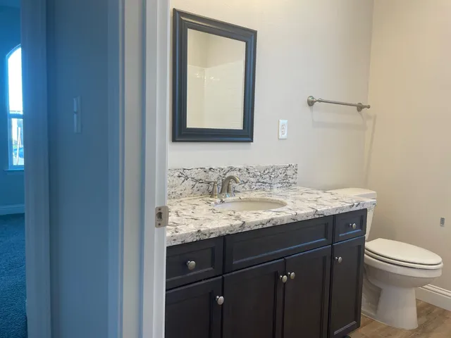 a bathroom with a granite countertop sink and a toilet