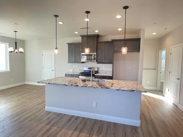 a view of a kitchen island a sink and a wooden floor