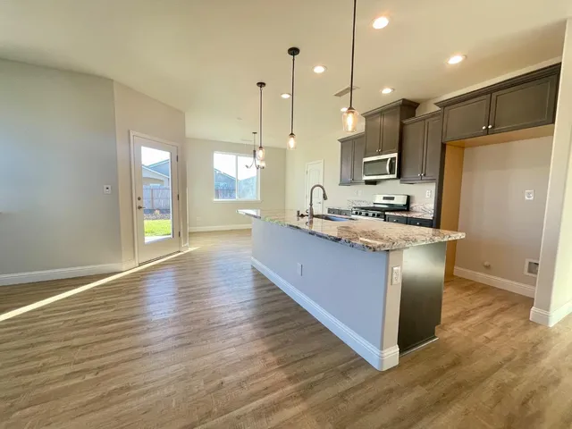 a kitchen with kitchen island granite countertop wooden floors and a sink