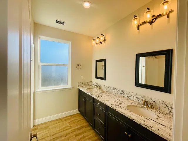 a bathroom with a granite countertop double vanity sink and mirror