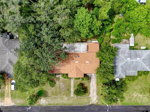 an aerial view of a house with a yard and large trees