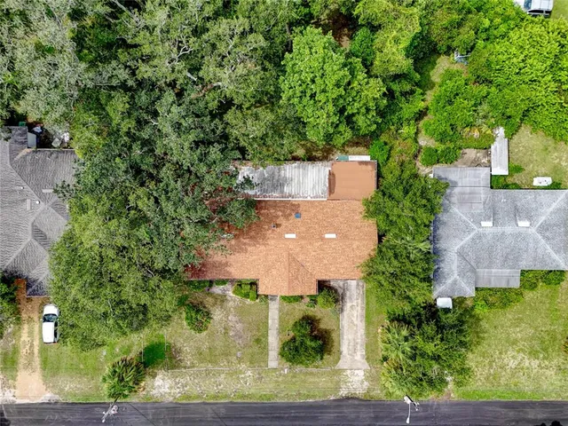 an aerial view of a house with a yard and large trees