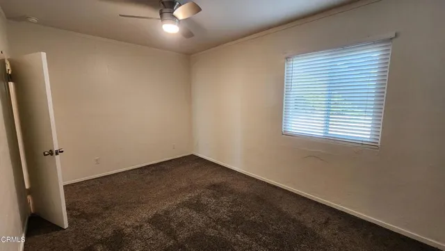 an empty room with a window and a ceiling fan