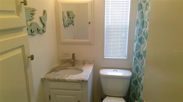 a bathroom with a granite countertop toilet and a sink