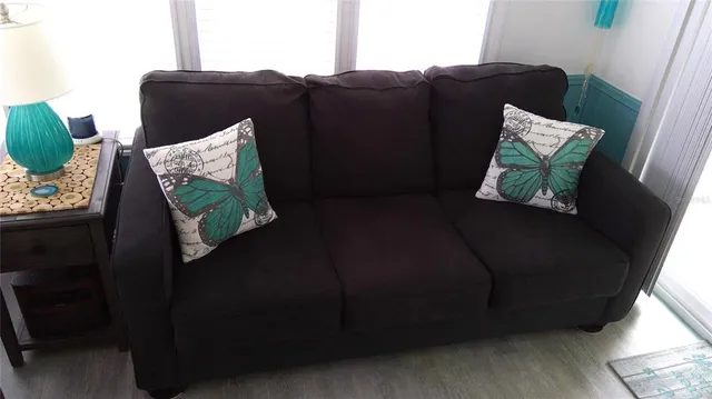 a black leather couch sitting in a bedroom next to a window