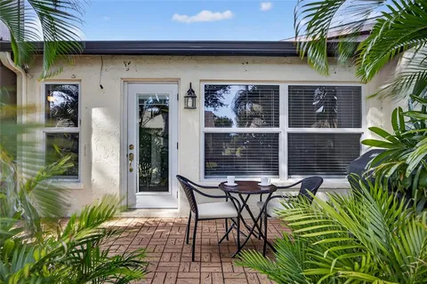 a patio with table and chairs and potted plants