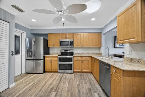 a kitchen with stainless steel appliances granite countertop a sink stove refrigerator and cabinets