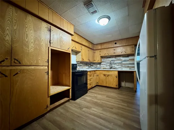 a kitchen with stainless steel appliances granite countertop a refrigerator a oven and a sink with wooden floor