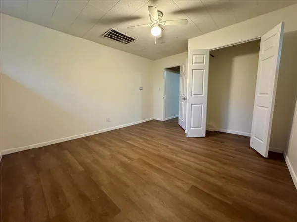 an empty room with wooden floor and ceiling fan