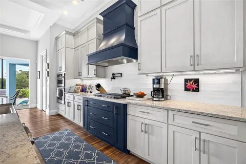 a kitchen with stainless steel appliances granite countertop a dining table chairs and white cabinets