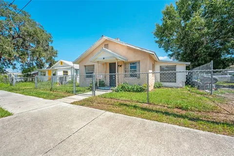 a view of a house with a yard and large tree
