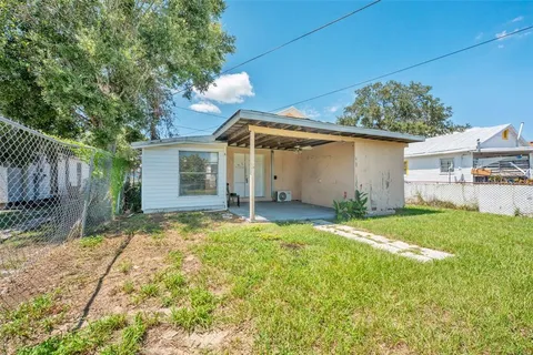 a backyard of a house with plants and large tree
