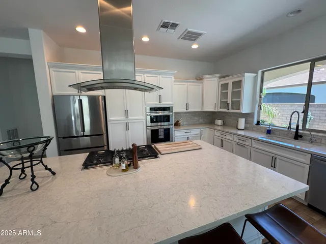 a kitchen with stainless steel appliances kitchen island granite countertop a sink chairs and cabinets