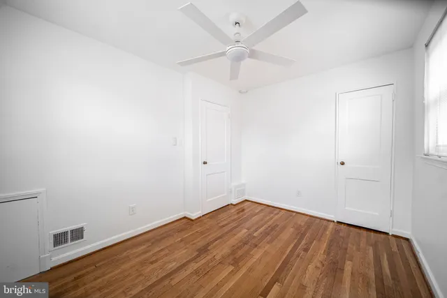a view of a room with wooden floor and a ceiling fan