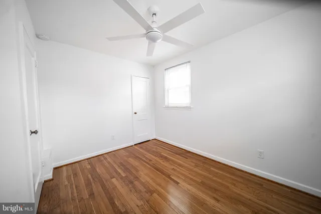 an empty room with a ceiling fan and wooden floor