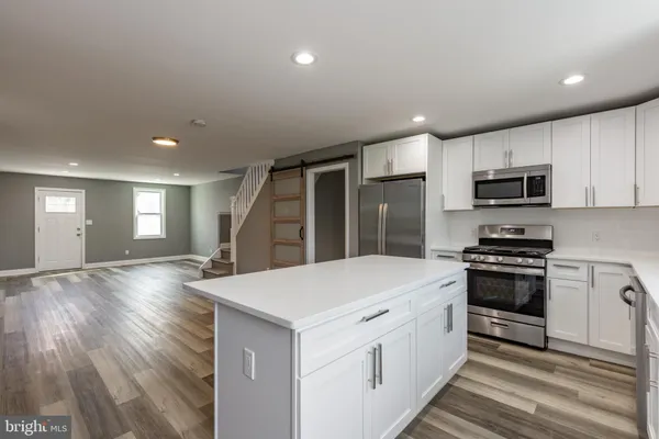 a large kitchen with stainless steel appliances granite countertop a lot of counter space and wooden floor
