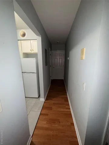 a view of a hallway with wooden floor and a kitchen