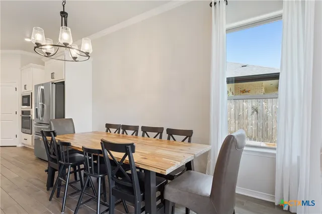 a view of a dining room with furniture a chandelier and wooden floor