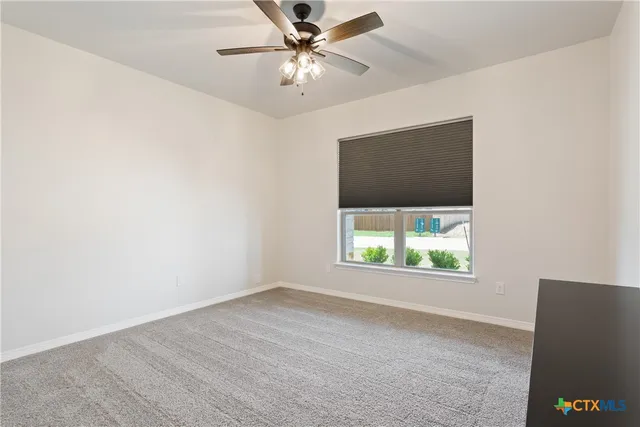 an empty room with a window and a ceiling fan