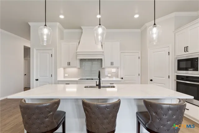 a kitchen with stainless steel appliances granite countertop a sink a stove a refrigerator and chairs