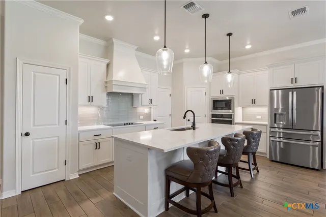 a kitchen with kitchen island granite countertop a sink a center island a refrigerator and wooden floor