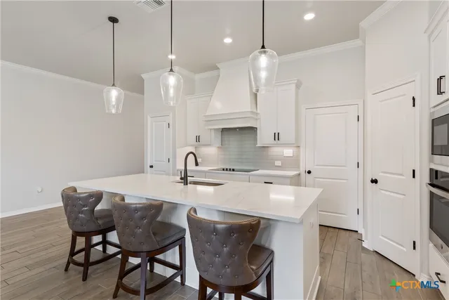 a kitchen with a sink chandelier and living room view