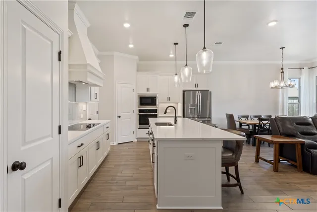 an open kitchen with granite countertop a stove top oven a sink dishwasher and a refrigerator with wooden floor