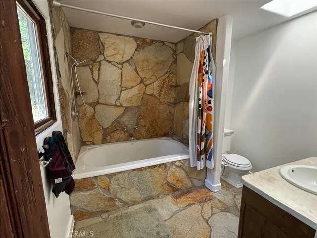 a bath room with a toilet and a shower curtain