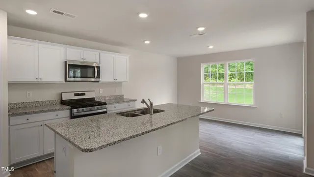 a kitchen with granite countertop stainless steel appliances a stove a sink a microwave a refrigerator and a counter