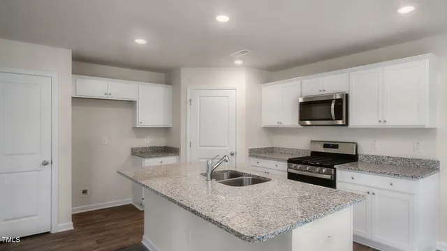 a kitchen with granite countertop a sink and a stove top oven with wooden floor